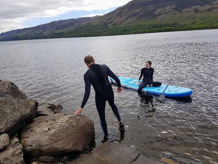Guest couple paddleboard from Brair Cottages slipway in to Loch Earn